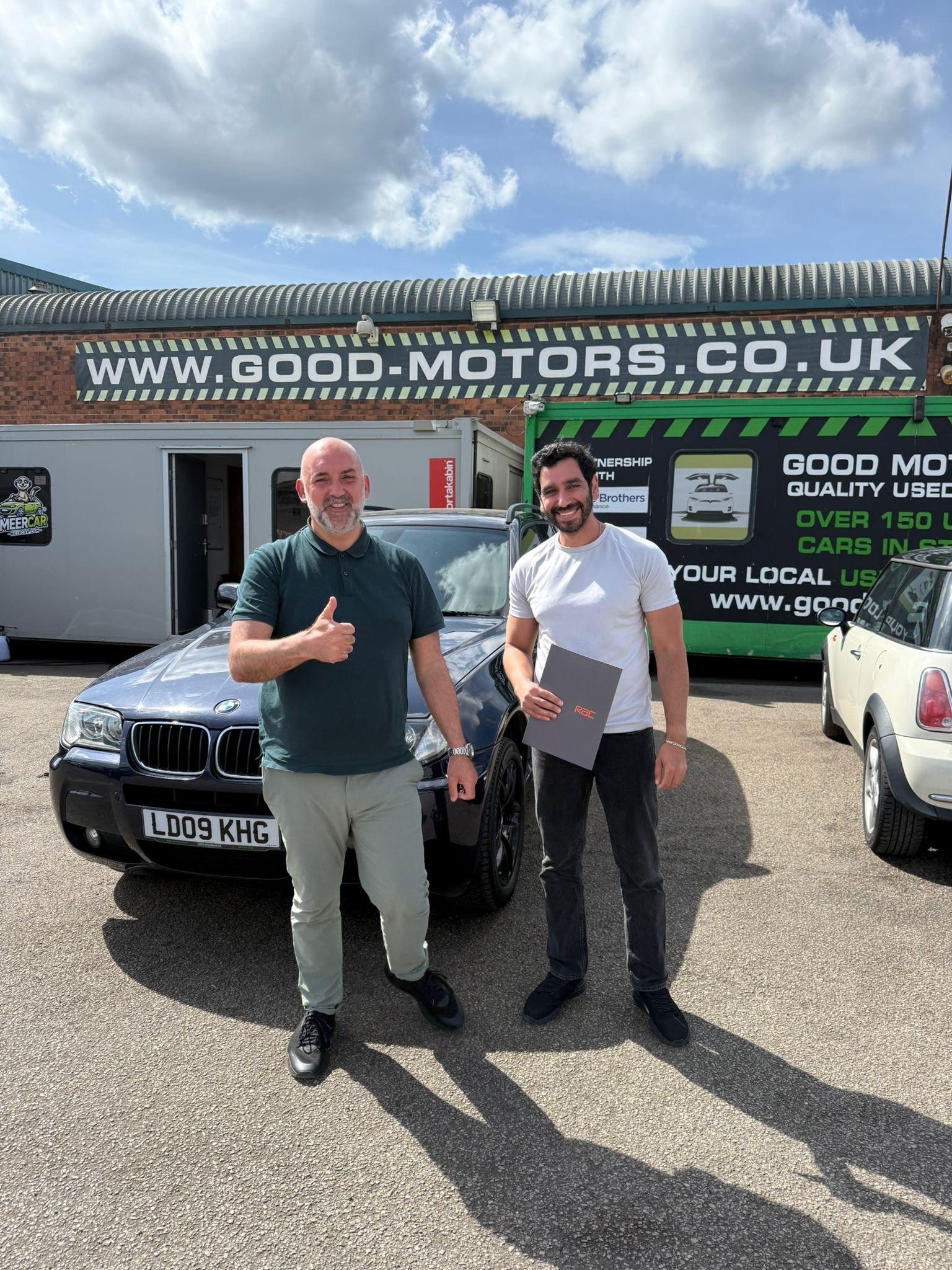 two men standing in front of a car